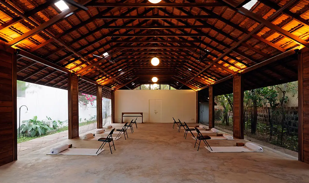 The yoga pavilion in the evening: a long timber roof over an open floor, set for a class